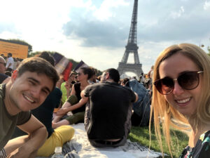 Sentados no Campos de Marte para nosso piquenique com a torre eiffel e milhares de pessoas de fundo